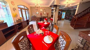 A dining area with red tablecloths, wooden chairs, and a chandelier. - Casona Puno (Puno)