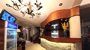 A reception area with a modern design, including a curved reception desk, a chandelier, and a refrigerator stocked with beverages. - Casona Puno (Puno)