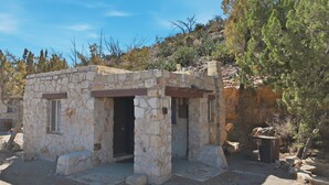A stone building with a door and windows, surrounded by trees and rocky terrain. - The Sunrise Studio - 1 Queen Bed (Truth or Consequences)