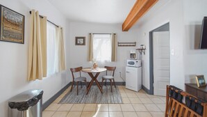 Una cocina compacta con una mesa de comedor, sillas, un refrigerador y un cubo de basura.
