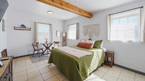 Un dormitorio con cama, escritorio, silla, mesita y ventana.