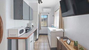 A compact kitchen with a microwave, coffee maker, and a small sink.