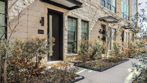 Un bâtiment en pierre avec une porte d’entrée sombre, portant le numéro 268, et un petit jardin agrémenté de diverses plantes.