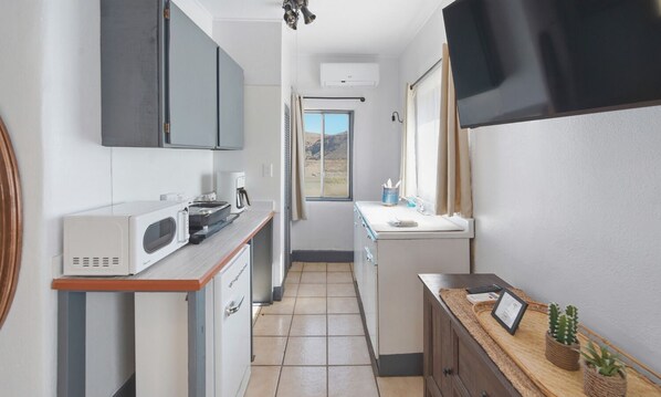 A compact kitchen with a microwave, coffee maker, and a small sink.