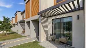 A modern building with a patio area featuring outdoor seating and a glass door entrance. - Family townhouse w/ pool & workspace (Kissimmee)