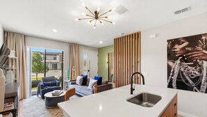 A modern living room with a sofa, coffee table, and a TV on a stand. - Family townhouse w/ pool & workspace (Kissimmee)