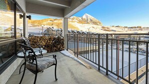 Een balkon met uitzicht op een besneeuwde berg en een parkeerplaats.