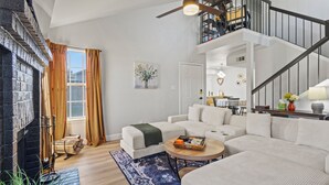 A spacious living room with a fireplace, a staircase, and a view of the outdoors.