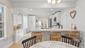 A modern kitchen with white cabinetry, a central island with bar stools, and pendant lighting.