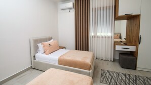 A modern hotel room with a bed, a bedside table, a mirror, and a wardrobe. - Wake Up to Lake Views – Cozy Comfort at Era e Liqenit” (Shkodër)