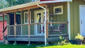 A single-story house with a porch, a front door, and a small fenced area. - 3 Rivers Farm Guest Cottage. Charming Farm Stay cottage in Deming, Wa, (Deming)