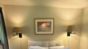 A neatly made bed with white bedding and a red accent pillow, flanked by two bedside tables with lamps, a framed picture above the bed, and a small nightstand with a tissue box. - 3 Rivers Farm Guest Cottage. Charming Farm Stay cottage in Deming, Wa, (Deming)