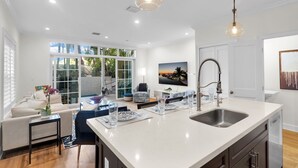 Una cocina moderna con una isla grande, un comedor con mesa y sillas, y vistas al exterior a través de amplios ventanales.