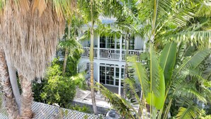 Un edificio de dos plantas con balcón, rodeado de exuberante vegetación tropical.