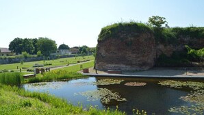 A serene landscape with a pond, grassy areas, and a large rock formation. - Oradea Gateway | 3BR by River | Quick Airport Exit (Oradea)