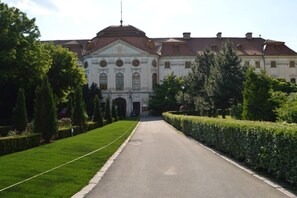 Ein großes, historisches Gebäude mit symmetrischer Fassade, einem zentralen Eingang und einem gepflegten Rasen.