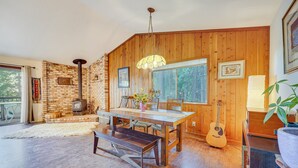 Un coin repas chaleureux avec une table en bois, des bancs et une guitare.