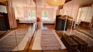 Habitación con pared espejada, dos camas, suelo de madera y lámpara colgante.