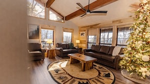 A cozy living room with a fireplace, leather sofas, a coffee table, and a Christmas tree. - Smoky Views & Game 4 BR Cabin w Hot Tub Near Wears Valley! (Sevierville)