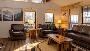 A cozy living room with leather sofas, wooden coffee table, and a rug with animal prints. - Smoky Views & Game 4 BR Cabin w Hot Tub Near Wears Valley! (Sevierville)