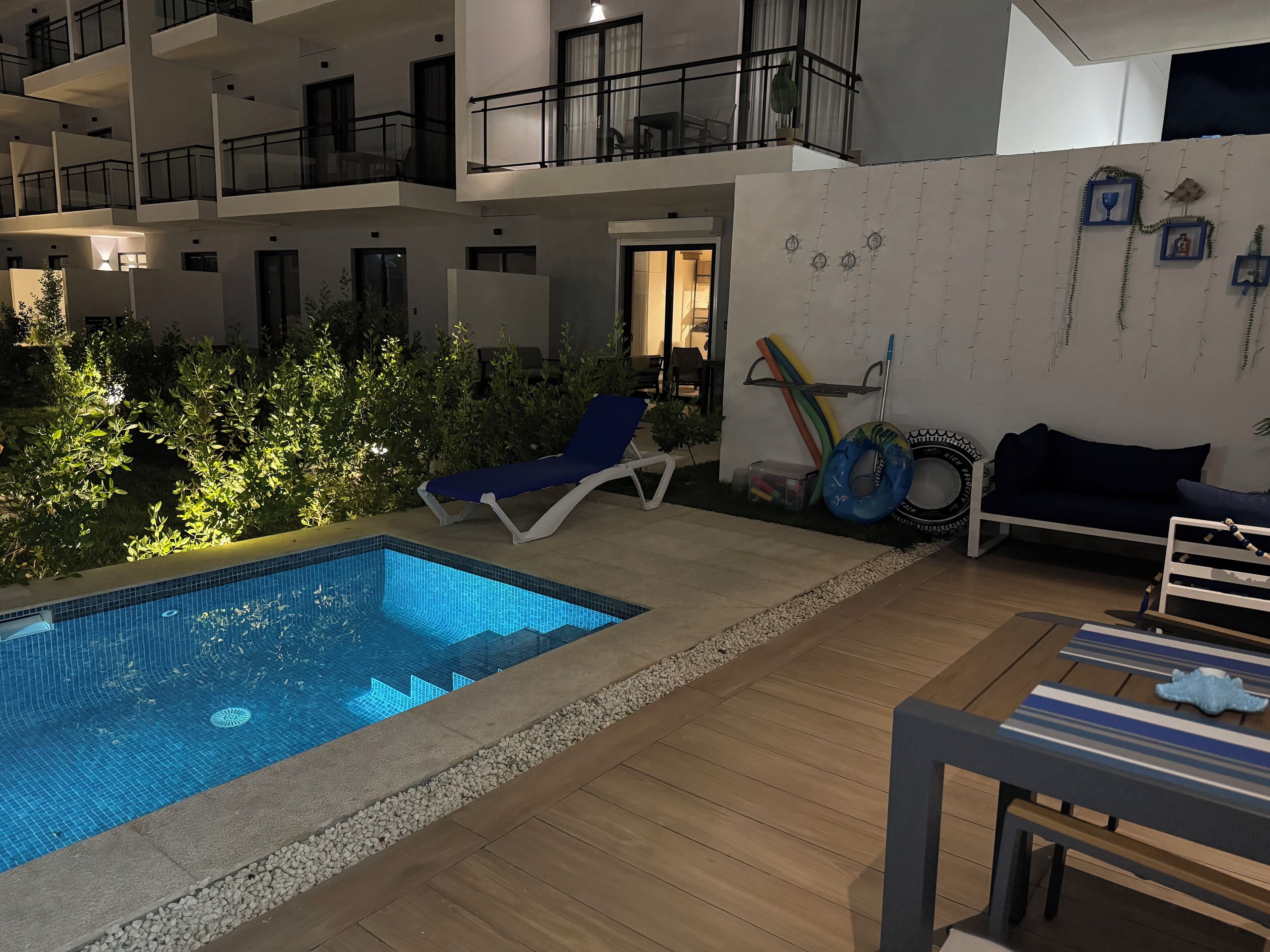 Um apartamento moderno com uma piscina pequena, uma espreguiçadeira e uma mesa de jantar.