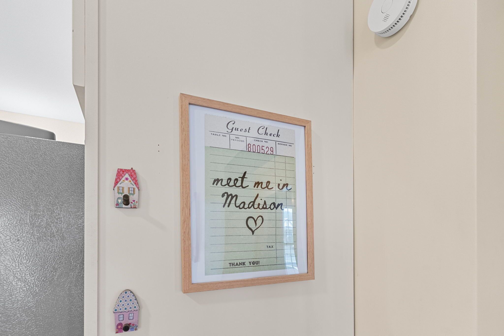 A framed guest check with a handwritten note saying "meet me in Madison" and a heart symbol.