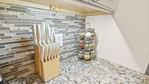 A kitchen with a granite countertop, a knife block, and a spice rack. - The Main Stay - Steps from Ohio River, Shopping, & Dining on Main St (Madison)