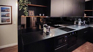 Una cuina moderna amb armaris foscos, una illa central i forn integrat.