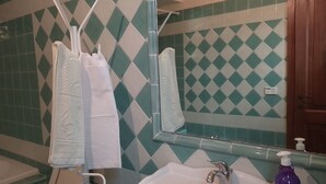 Ein Badezimmer mit einem weißen Waschbecken, einem Spiegel und einer Duschkabine.