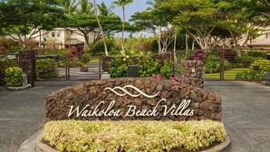 A sign for Waikoloa Beach Villas with a stone wall and landscaped garden. - Waikoloa Beach Villas K2 - Golf Course Front, Walk to Beach (Waikoloa)