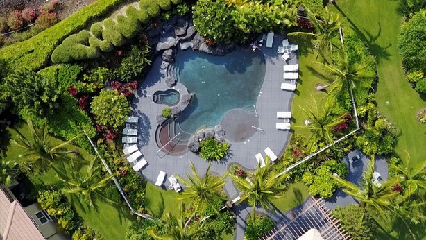 An aerial view of a resort with a central swimming pool, surrounded by lounge chairs and palm trees. - Waikoloa Beach Villas K2 - Golf Course Front, Walk to Beach (Waikoloa)