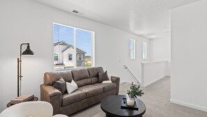 Ein modernes Wohnzimmer mit Ledersofa, rundem Couchtisch und Stehlampe.