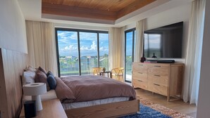 Een moderne slaapkamer met een groot bed, houten meubels, een televisie en een balkon met uitzicht.