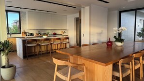 Een moderne keuken met witte kastjes, een houten keukeneiland en barkrukken.