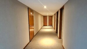 Un corridoio stretto, rivestito di tappeto, con porte in legno su entrambi i lati che conduce a una stanza in fondo.
