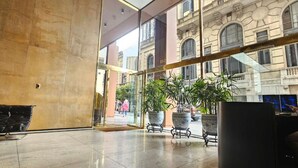Un'ampia hall con soffitto alto, grandi finestre e un'area salotto con un divano in pelle.