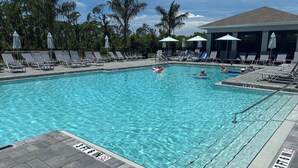 Una piscina con acqua cristallina, circondata da lettini e ombrelloni, con palme sullo sfondo.