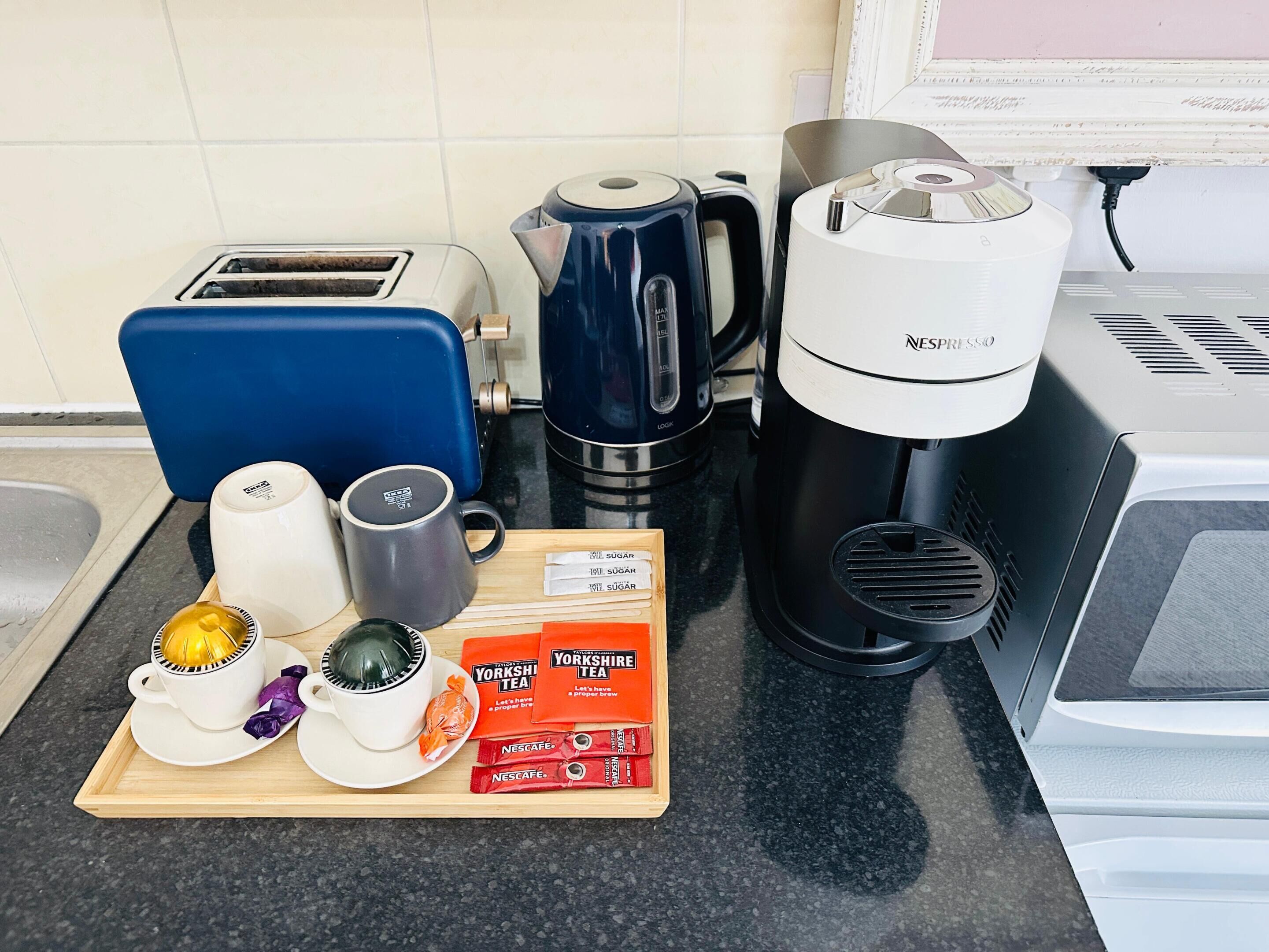 Una encimera de cocina con tostadora, cafetera, hervidor y bolsitas de té.