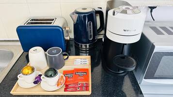Una encimera de cocina con tostadora, cafetera, hervidor y bolsitas de té.