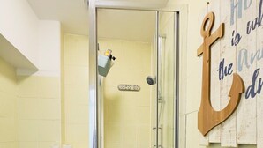 Kylpyhuone, jossa on wc, suihku ja seinälle kiinnitetty opastekyltti.