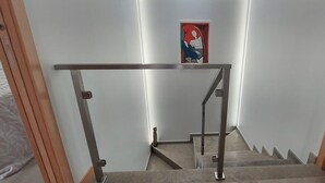 En trappe med gelænder i metal og et billede på væggen.