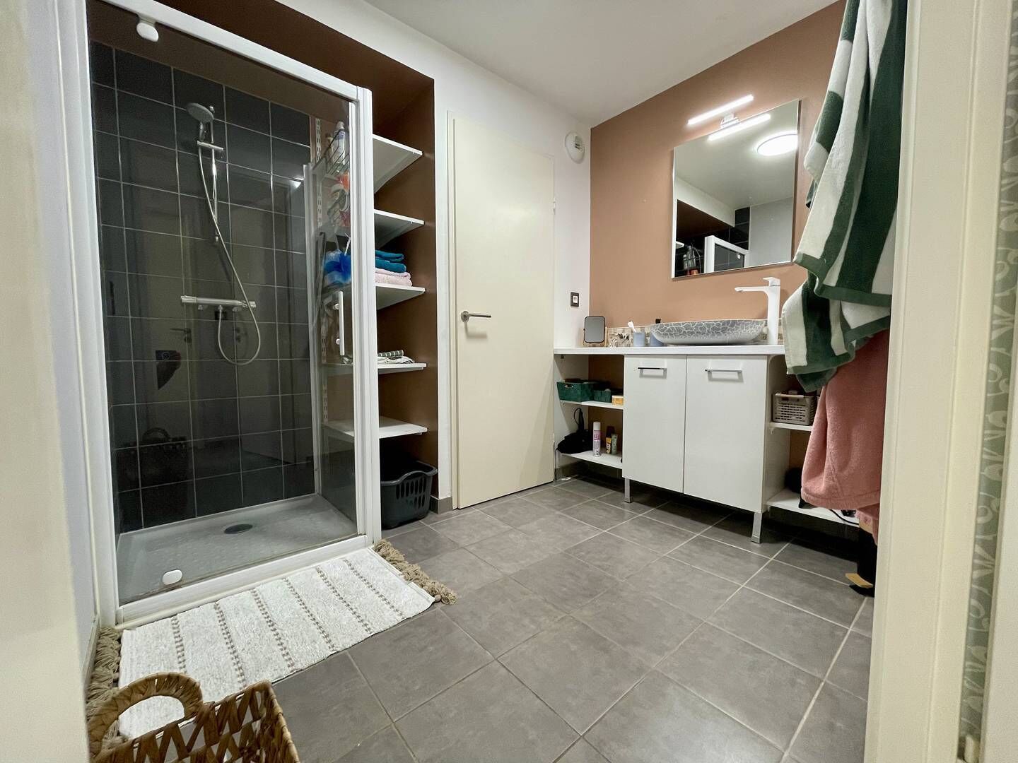 A bathroom with a glass shower enclosure, a white sink, and a mirror above it.