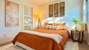 Ein Schlafzimmer mit Bett, Deckenventilator, Nachttisch, Lampe und einem großen Fenster.