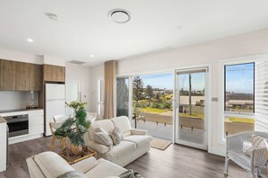 A modern apartment with a kitchen, living area, and balcony with a city view. - Little Blowhole Kiama, Garden Apartment (Kiama)