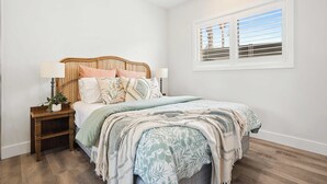 A bedroom with a bed, bedside tables, and a window. - Little Blowhole Kiama, Garden Apartment (Kiama)