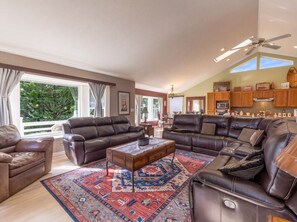 A spacious living area with leather sofas, a patterned rug, and a view of the outdoors. - Siuslaw River House *Casino*River*Beach*Pets*Pool (Florence)