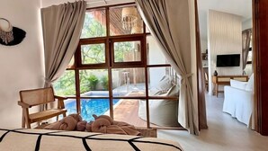 A bedroom with a large window, a bed, a chair, and a view of an outdoor swimming pool. - Villa Uluwatu - Belle Vue Jungle, Villa 23 (Koh Samui)