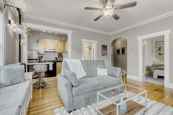 Un salon moderne avec un canapé gris, une table basse et un ventilateur de plafond.
