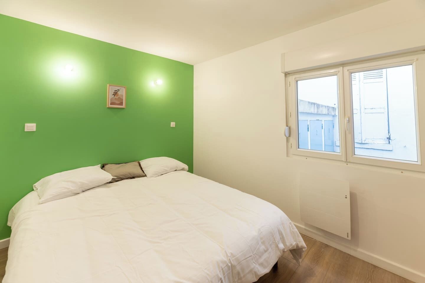 Une chambre à coucher avec un lit, une fenêtre et un mur vert.