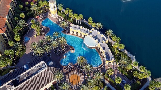 Ein Luftbild eines Resorts mit mehreren Schwimmbecken, Palmen und einem Turm.
